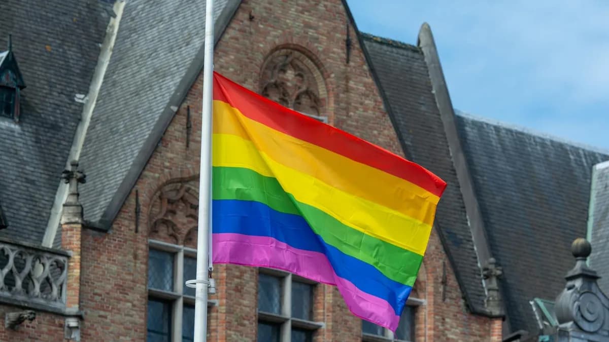 Bright rainbow pride flag waving against a historic architectural building, symbolizing diversity and inclusion.