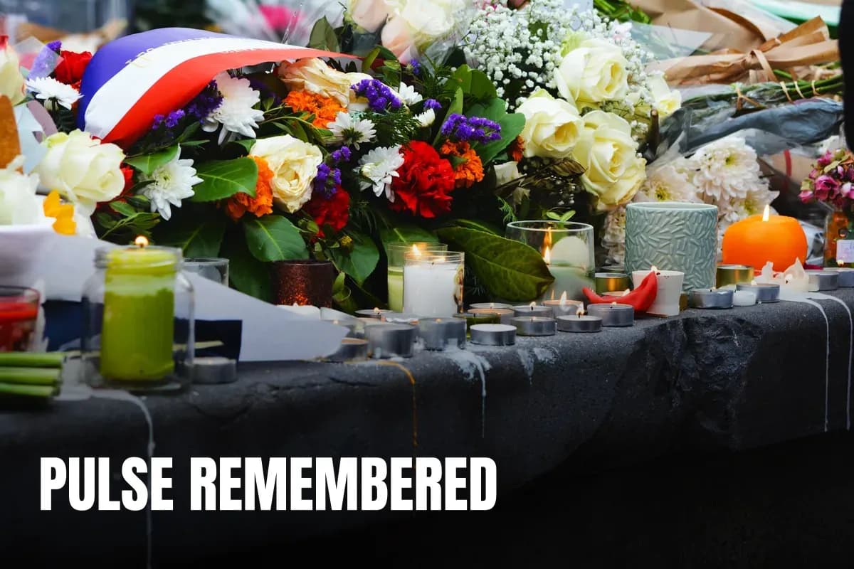A serene memorial setup with candles and floral tributes on a stone surface outdoors.