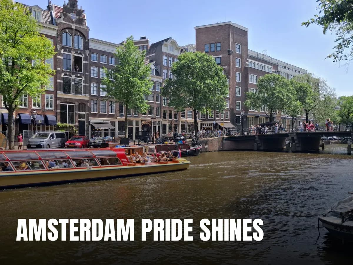Lively Amsterdam canal view with tourist boats and historic buildings under a sunny sky.