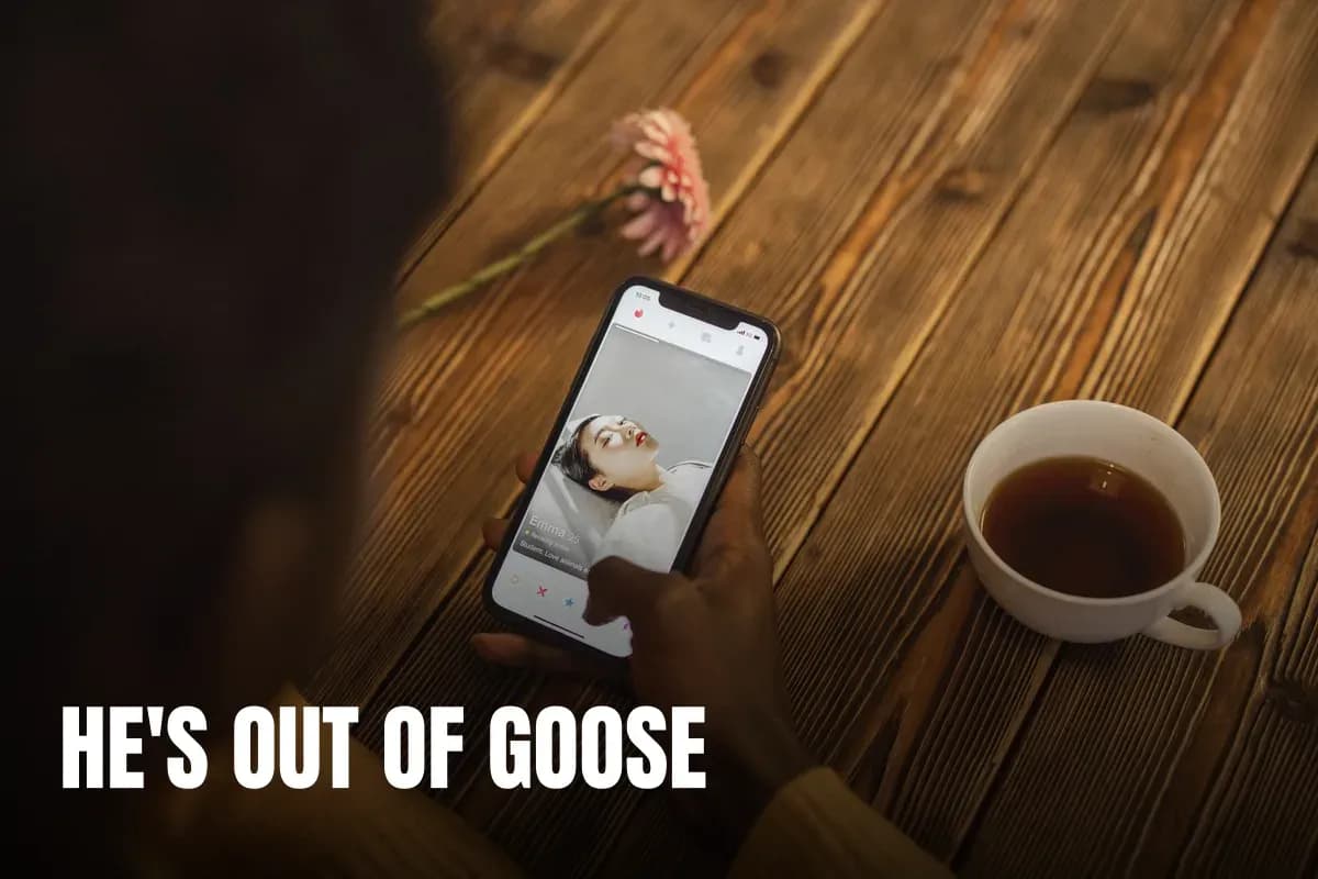 An individual using a dating app on a smartphone with a cup of tea nearby on a wooden table.