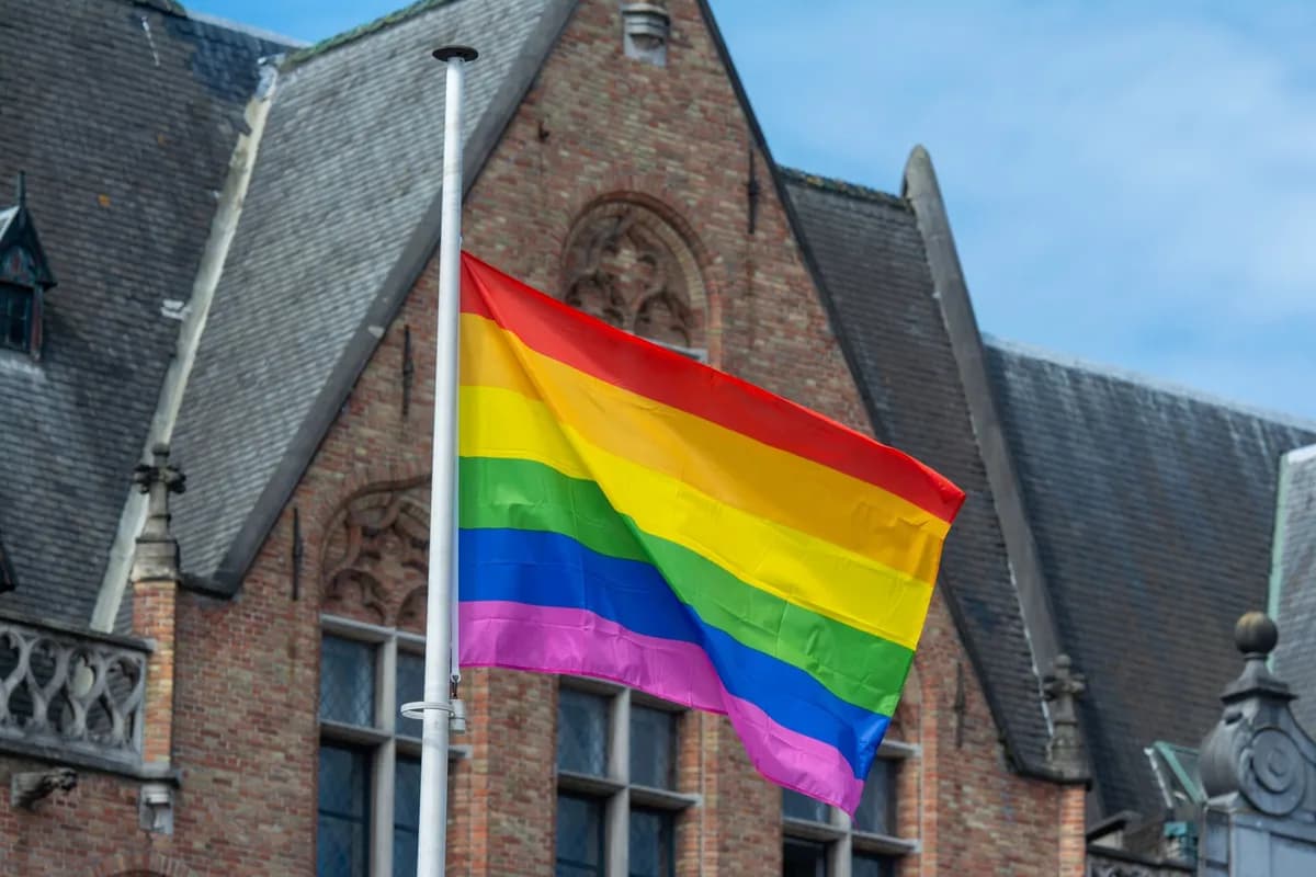 Bright rainbow pride flag waving against a historic architectural building, symbolizing diversity and inclusion.