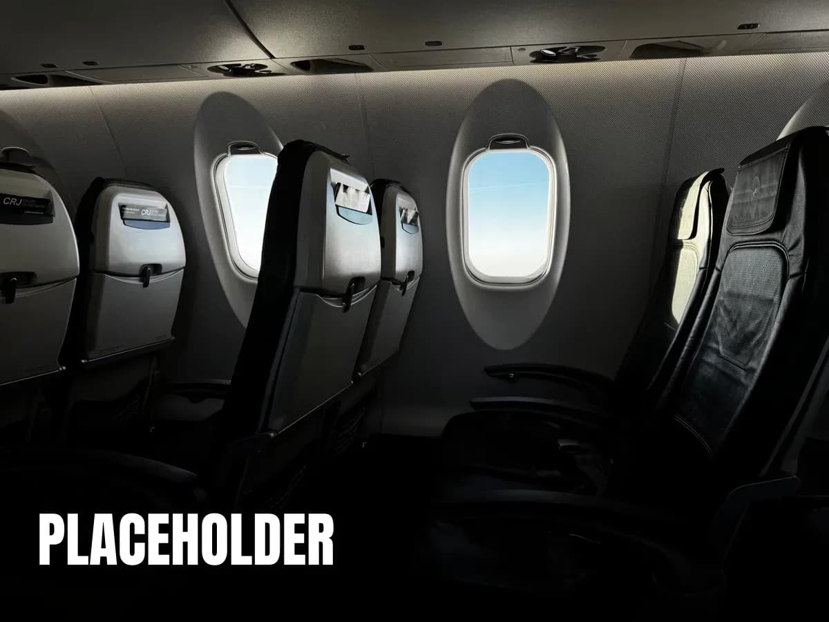 Interior of an empty airplane cabin with a bright sky visible through the window.